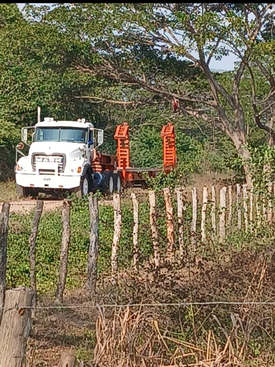 Chuto blanco con estructura de carga naranja junto a una cerca
