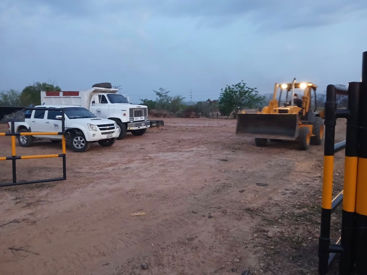 Camionetas, camiones y una pala cargadora en el patio de equipos