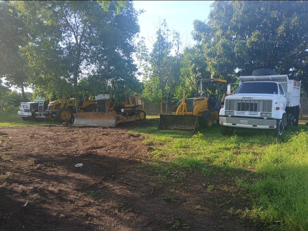 Tractores amarillos y camión de volteo estacionados junto a una zona de trabajo